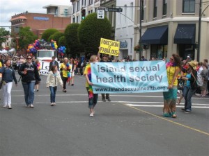 Two female staff members carrying ISHS's banner in a parade in Victoria BC