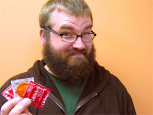 Male with a beard holding condoms