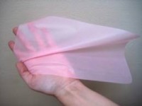hand holding a pink latex oral dam