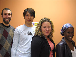 two males and two females standing together appearing relaxed and optimistic